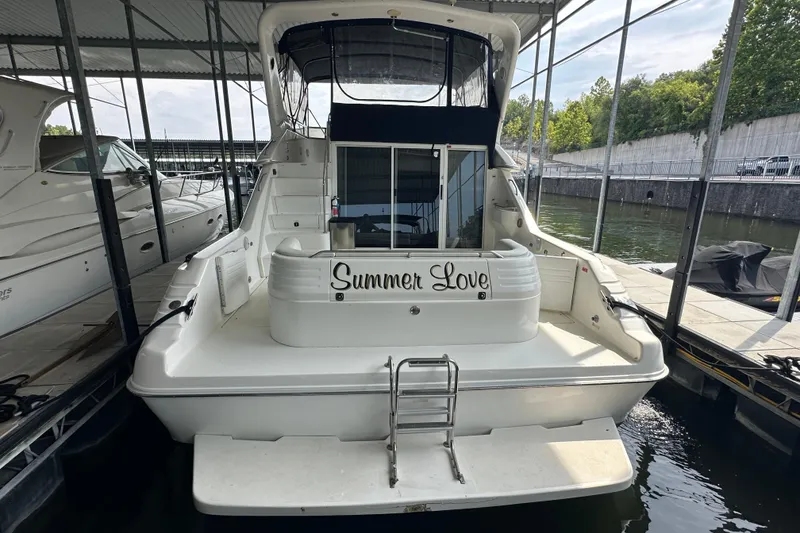 Slide: The Image of 1995 Sea Ray 440 Express Bridge yacht docked, named "Summer Love," with a spacious rear deck. - 7