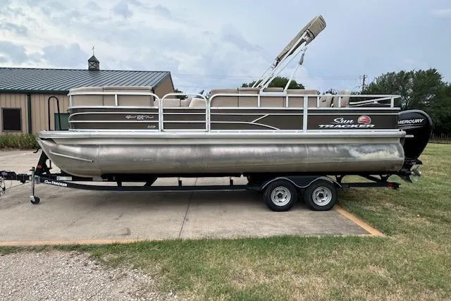 Slide: The Image of 2018 Sun Tracker SportFish 22 XP3 pontoon boat on a trailer, parked outdoors. - 2