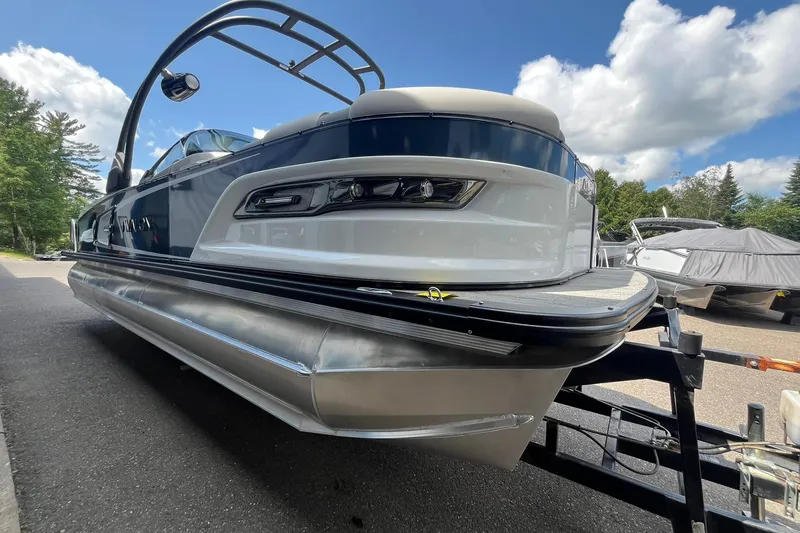 Slide: The Image of 2025 Avalon Excalibur Versatile Rear Bench Windshield boat on trailer, under blue sky. - 5