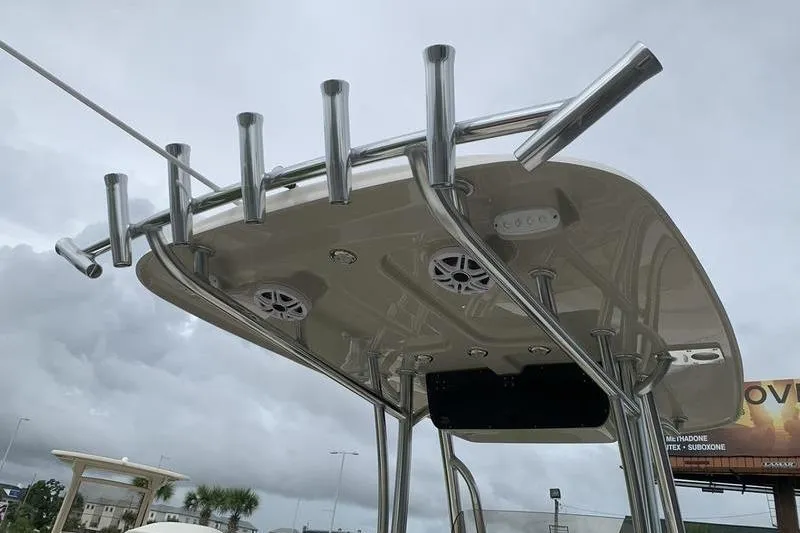 Slide: The Image of 2026 Bulls Bay 255CC boat T-top with rod holders and speakers under cloudy sky. - 16