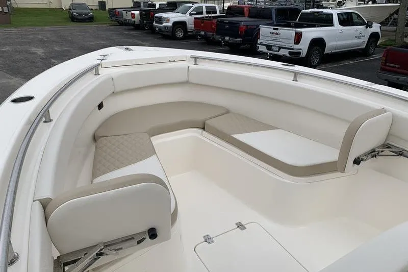 Slide: The Image of 2026 Bulls Bay 255CC boat interior with cushioned seating, parked trucks in background. - 26