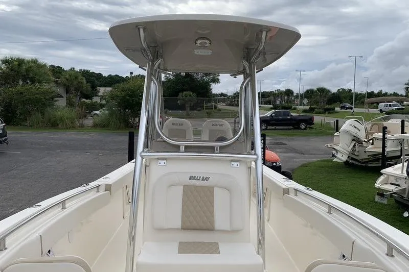 Slide: The Image of 2026 Bulls Bay 255CC boat with T-top and seating, parked outdoors. - 28