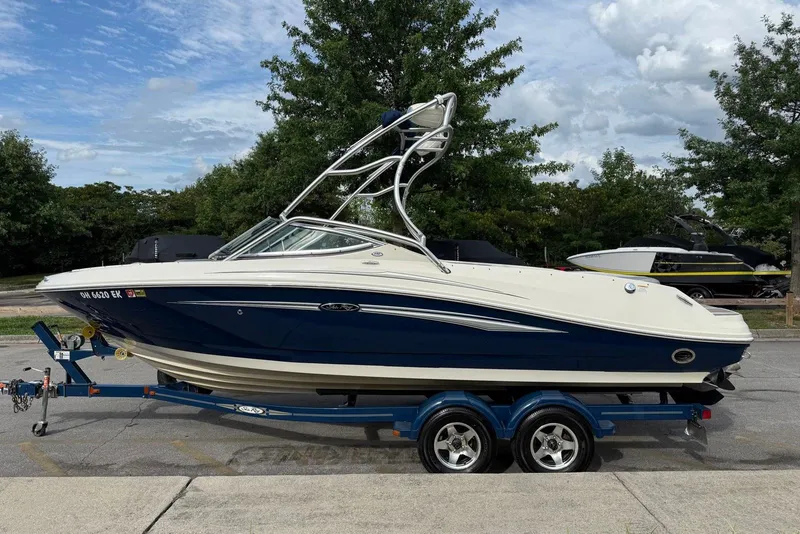 The Image of 2008 Sea Ray 230 Bow Rider Select on trailer, parked outdoors with trees in background. - 0