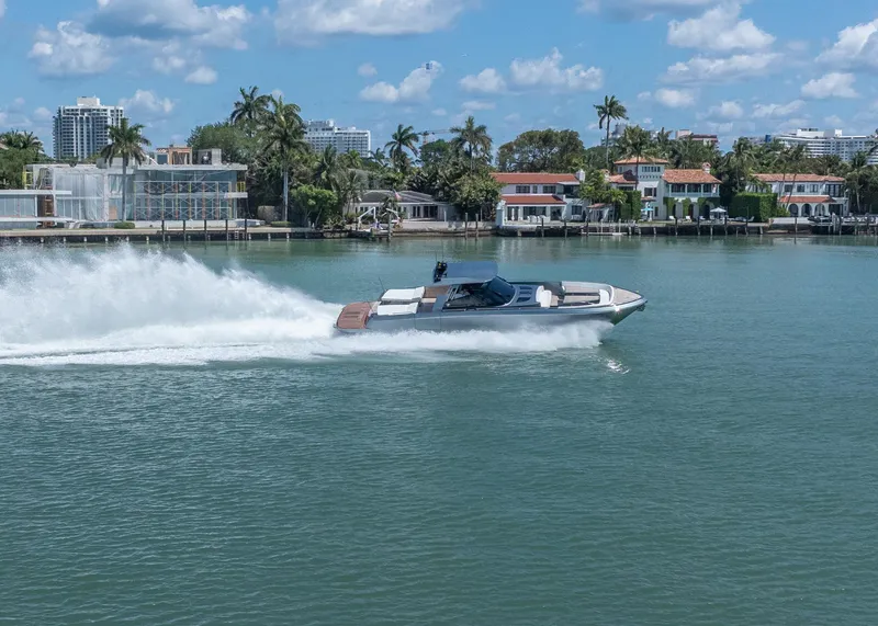 Slide: The Image of 2024 CNM CONTINENTAL 54 SuperSport yacht cruising on a sunny day near waterfront homes. - 15