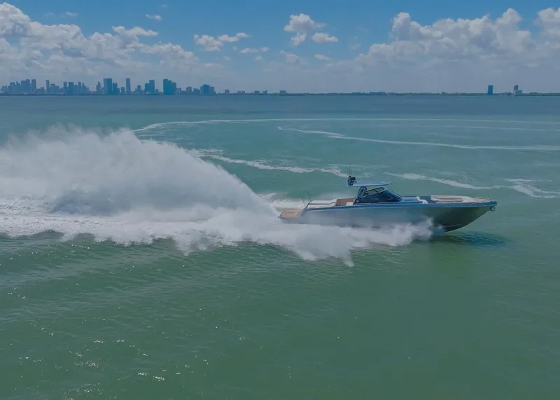 Slide: The Image of 2024 CNM CONTINENTAL 54 SuperSport yacht speeding on ocean with city skyline in background. - 4
