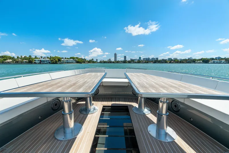 Slide: The Image of 2024 CNM CONTINENTAL 54 SuperSport yacht deck with dual tables, overlooking serene waters. - 46