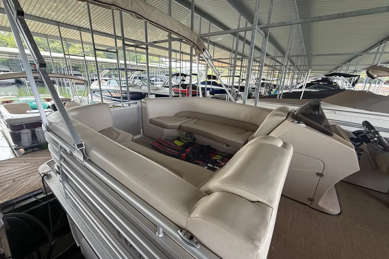 Slide: The Image of 2018 Harris FloteBote Solstice 240 pontoon boat with beige seating, docked in a covered marina. - 6