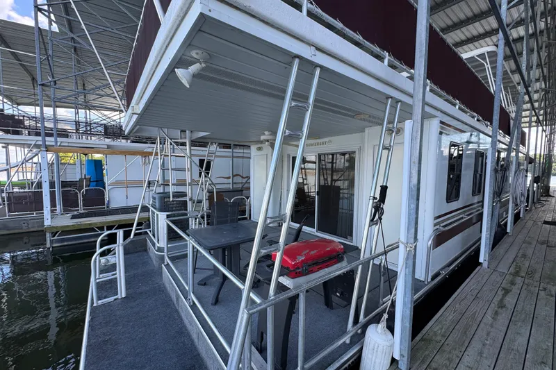 Slide: The Image of 2002 Sumerset houseboat on a serene lake with American flags and lush greenery. - 2