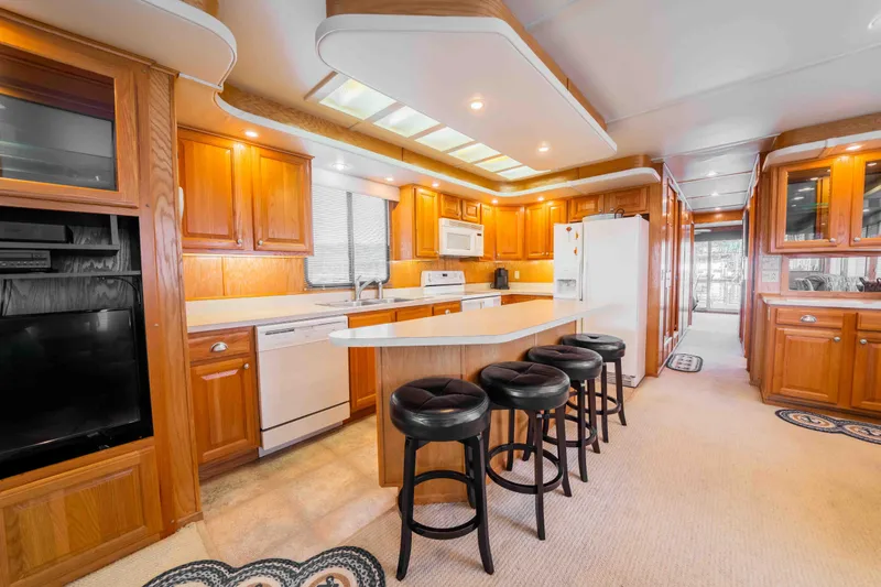 Slide: The Image of Luxurious 2002 Sumerset houseboat kitchen with wooden cabinetry, island, and bar stools. - 34