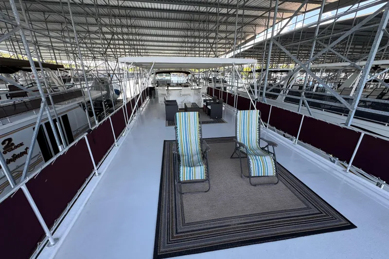 Slide: The Image of 2002 Sumerset houseboat on a serene lake with American flags and deck chairs. - 4