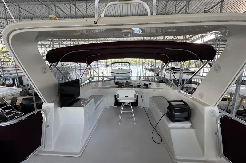 Slide: The Image of 2002 Sumerset houseboat on a serene lake, featuring a spacious deck with lounge chairs. - 5