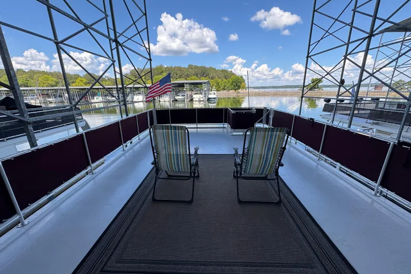 Slide: The Image of 2002 Sumerset houseboat on a scenic lake with American flags and outdoor seating. - 6