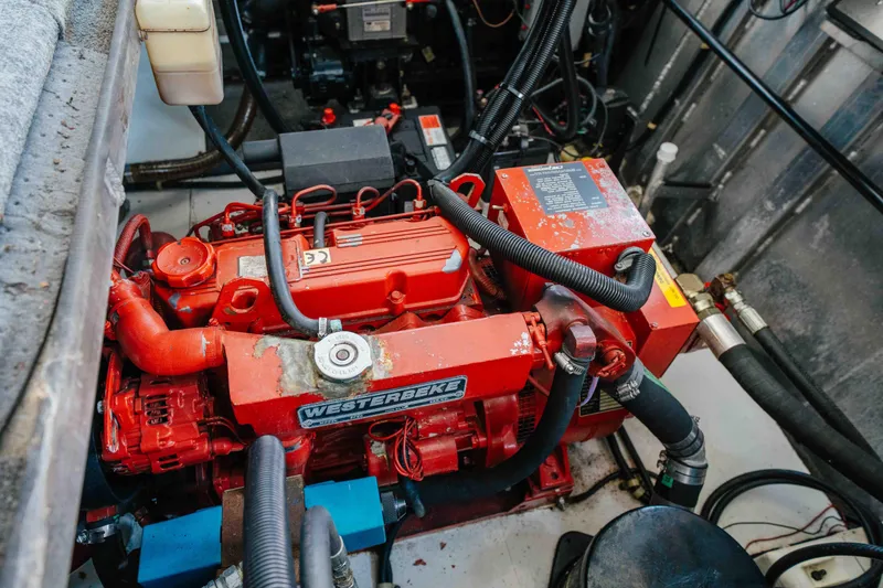 Slide: The Image of Engine room of a 2002 Sumerset Houseboat featuring a red Westerbeke generator. - 61