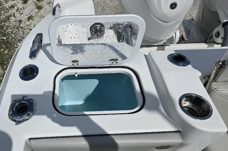 Slide: The Image of 2024 Pursuit DC 326 Dual Console boat with open storage compartment and cup holders. - 16