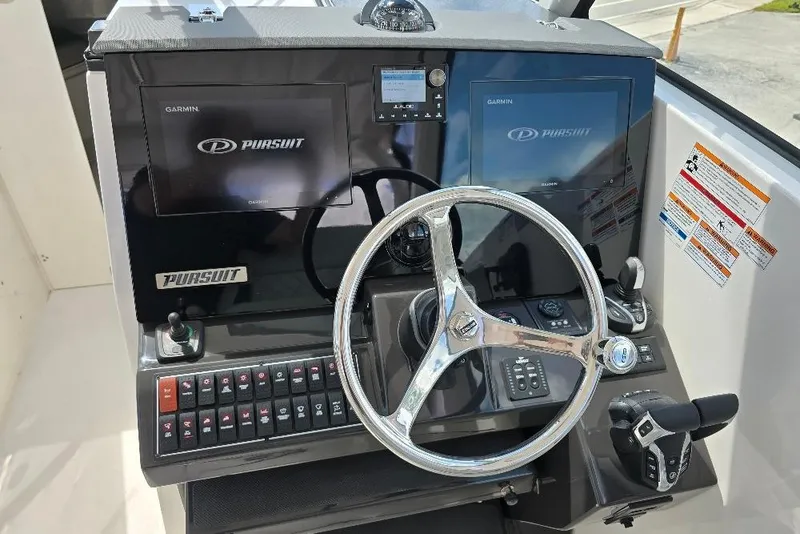 Slide: The Image of 2024 Pursuit DC 326 Dual Console helm with Garmin displays and steering wheel. - 2