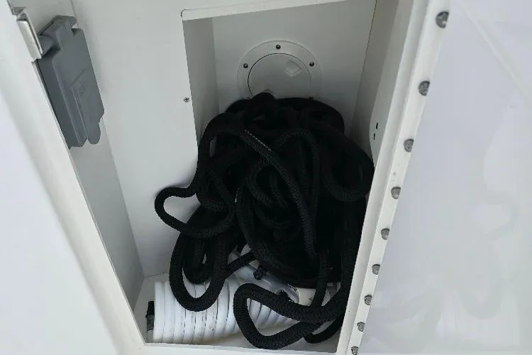 Slide: The Image of Storage compartment with coiled black rope on 2024 Pursuit DC 326 Dual Console boat. - 22