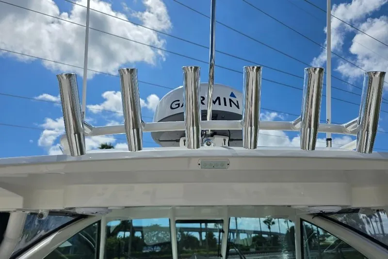 Slide: The Image of 2024 Pursuit DC 326 Dual Console boat with Garmin radar and rod holders against blue sky. - 29