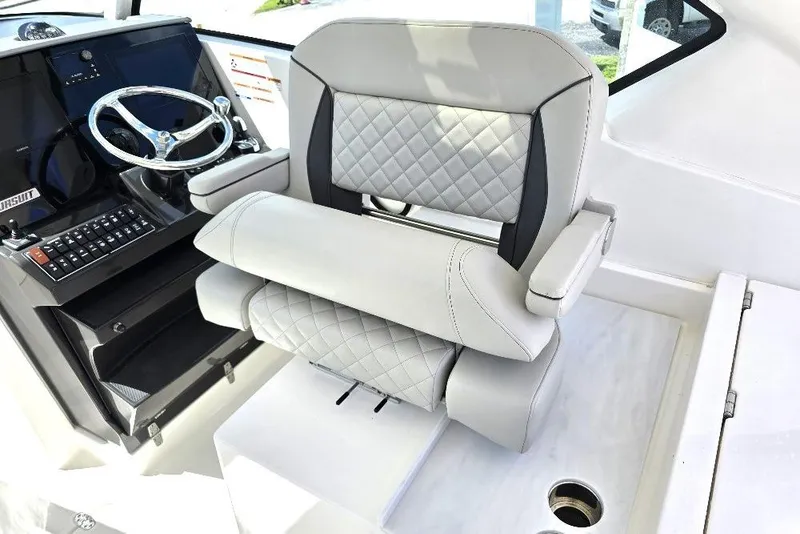 Slide: The Image of 2024 Pursuit DC 326 Dual Console helm seat with quilted upholstery and steering wheel. - 8