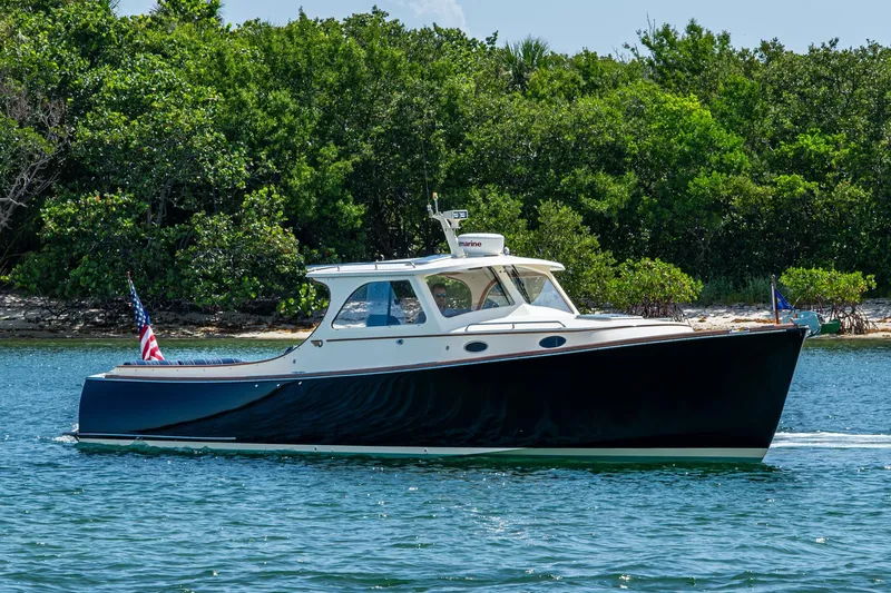 Slide: The Image of 2001 Hinckley Picnic Boat Classic cruising on water near lush green shoreline. - 21