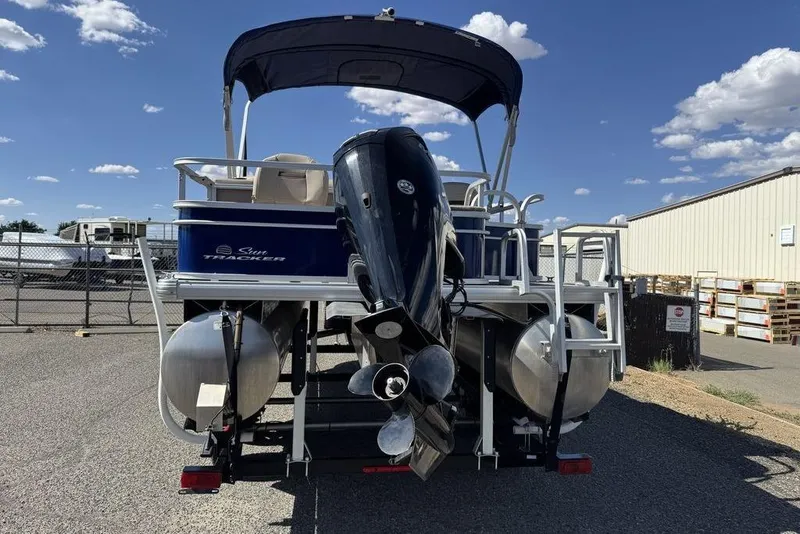 Slide: The Image of 2017 Sun Tracker FISHIN' BARGE® 20 DLX pontoon boat with outboard motor, parked outdoors. - 14