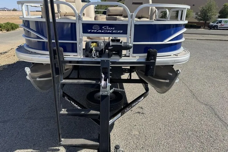 Slide: The Image of 2017 Sun Tracker FISHIN' BARGE® 20 DLX pontoon boat on trailer, parked outdoors. - 19