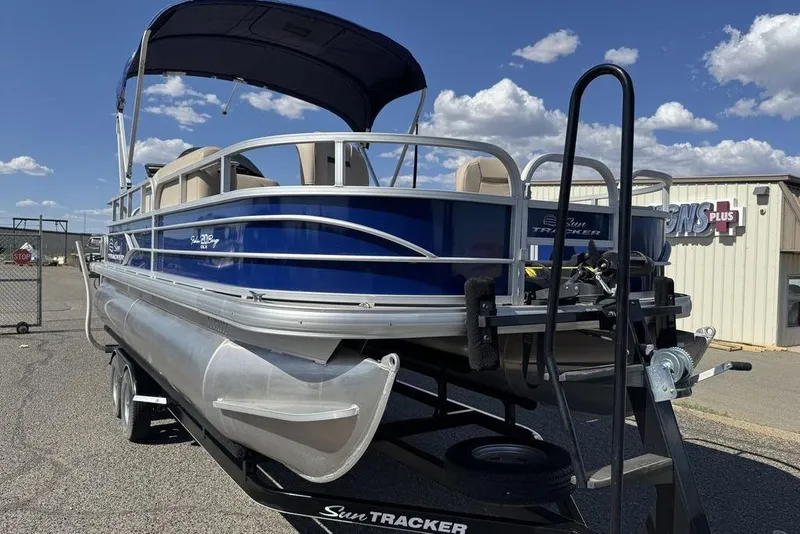 Slide: The Image of 2017 Sun Tracker FISHIN' BARGE® 20 DLX pontoon boat on trailer, under clear sky. - 59