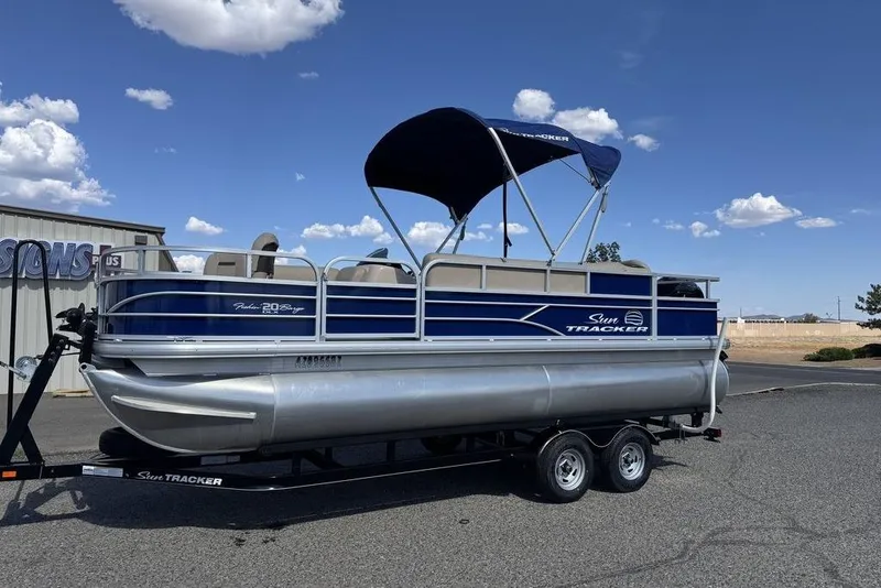Slide: The Image of 2017 Sun Tracker FISHIN' BARGE® 20 DLX pontoon boat on trailer, blue sky background. - 7