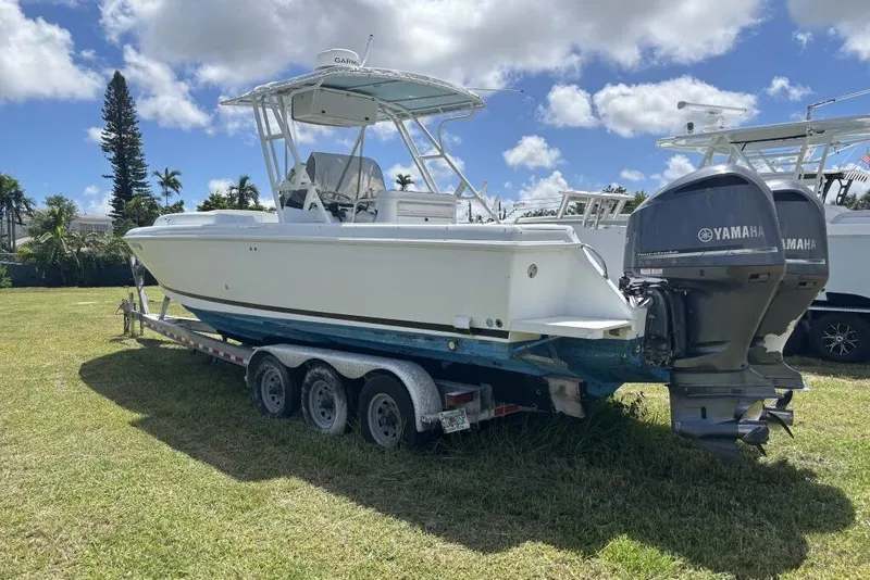 The Image of 2000 Intrepid 322 Cuddy boat on trailer with Yamaha engines, parked on grass. - 1