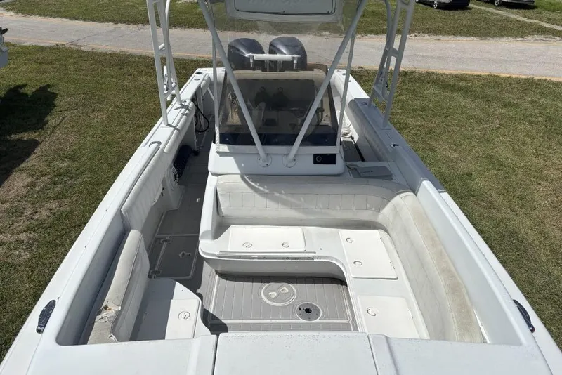 Slide: The Image of 2000 Intrepid 322 Cuddy boat interior with seating and helm, parked on grass. - 10