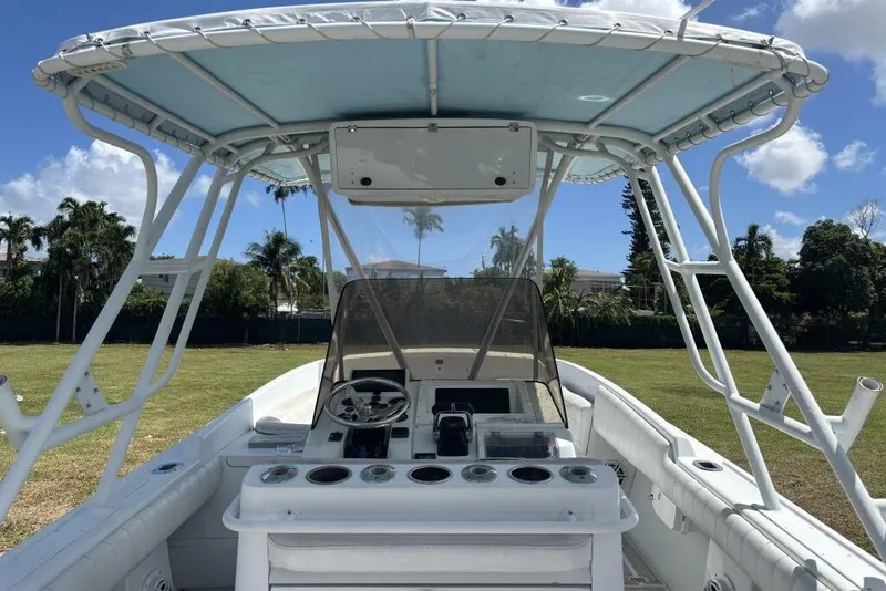 Slide: The Image of 2000 Intrepid 322 Cuddy boat interior with steering console and canopy, set against a grassy backdrop. - 18