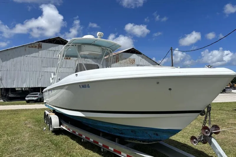 Slide: The Image of 2000 Intrepid 322 Cuddy boat on trailer, parked outdoors under blue sky. - 5