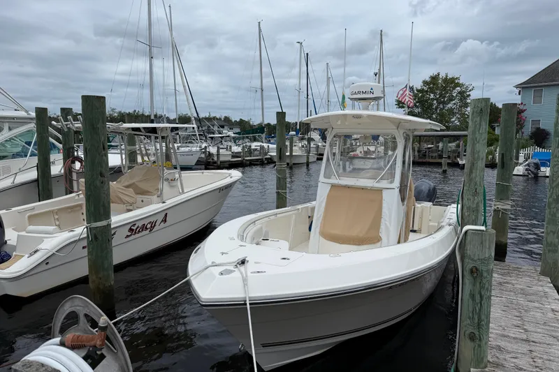 Slide: The Image of 2015 Cobia 256 Center Console boat docked at a marina with other vessels. - 15