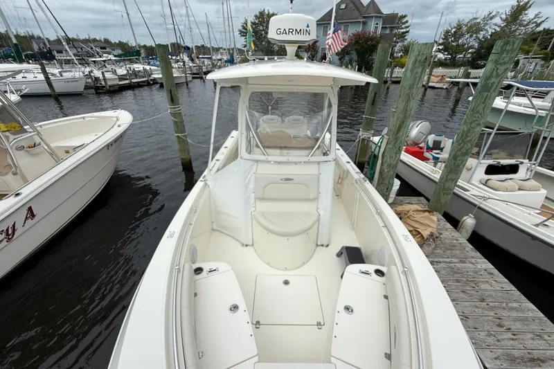 Slide: The Image of 2015 Cobia 256 Center Console boat docked at a marina with surrounding vessels. - 21