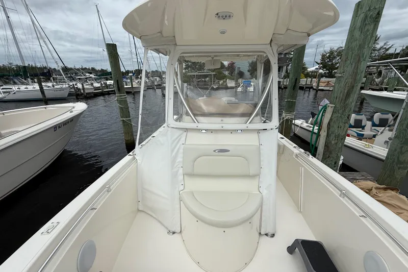 Slide: The Image of 2015 Cobia 256 Center Console boat docked at marina, featuring spacious seating and clear canopy. - 22