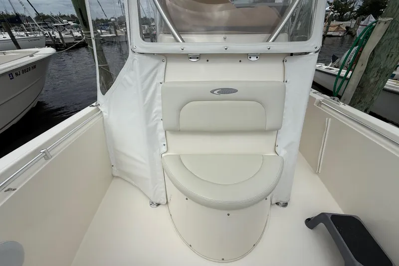 Slide: The Image of 2015 Cobia 256 Center Console boat interior with cushioned seating at marina. - 24