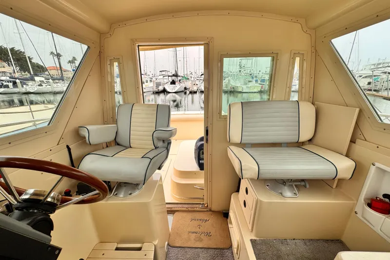 Slide: The Image of Interior of 2003 Albin 28 TE boat with two cushioned seats and marina view. - 19