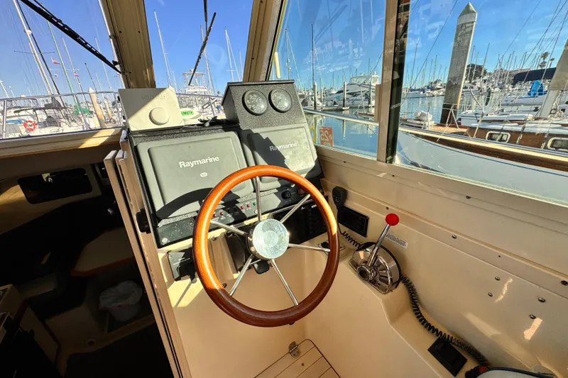 Slide: The Image of 2003 Albin 28 TE boat helm with Raymarine navigation, wooden steering wheel, marina view. - 20