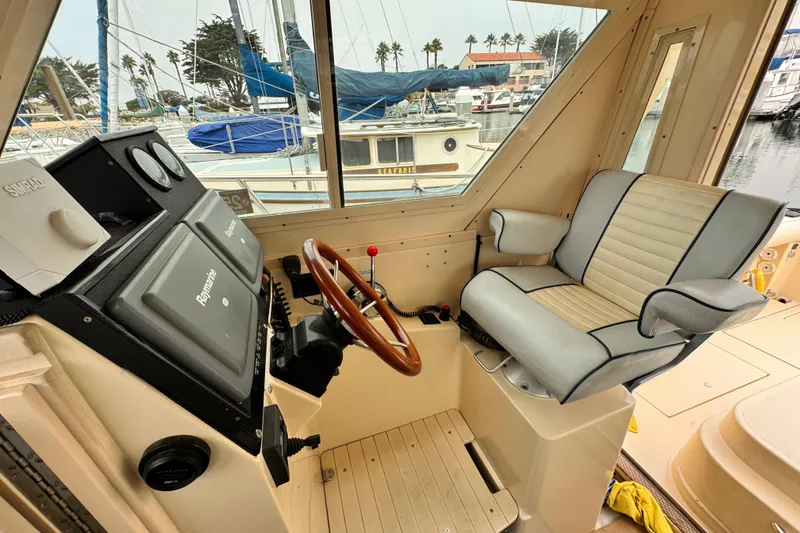 Slide: The Image of 2003 Albin 28 TE boat interior with steering wheel and captain's chair in marina setting. - 22