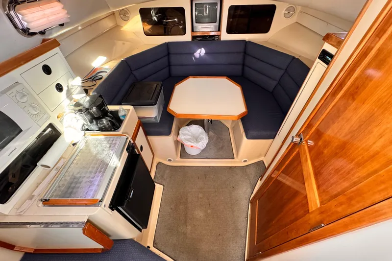 Slide: The Image of 2003 Albin 28 TE cabin interior with kitchenette, seating area, and wooden finishes. - 28