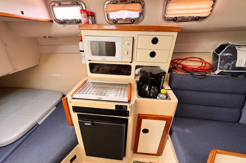 Slide: The Image of 2003 Albin 28 TE cabin interior with kitchenette, microwave, and seating area. - 29