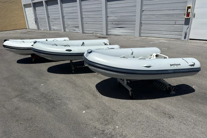 Slide: The Image of Three Geniuss 285 TILLER inflatable boats, 2025 model, parked on pavement near storage units. - 9