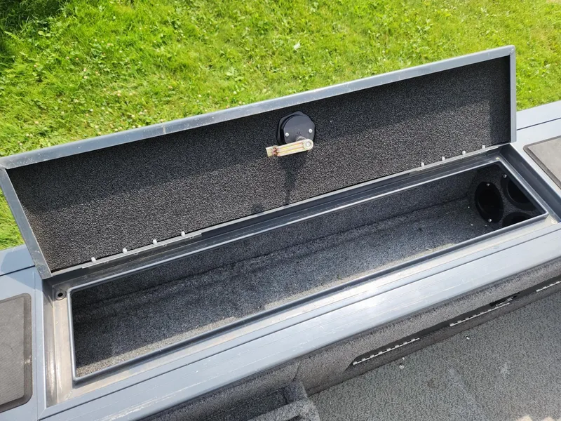 Slide: The Image of Open storage compartment on 2019 Tracker Targa V-18 Combo boat, with green grass background. - 22