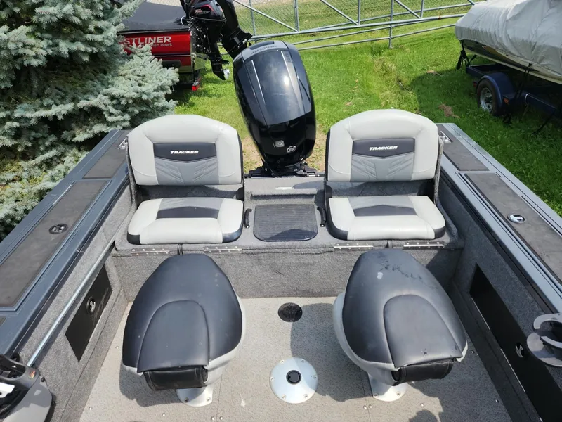 Slide: The Image of 2019 Tracker Targa V-18 Combo boat interior with seating and motor, parked on grass. - 6