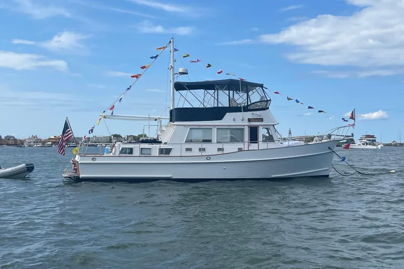 Slide: The Image of 2002 Grand Banks 42 Classic yacht adorned with flags, anchored in a scenic harbor. - 0