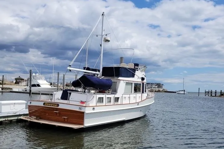 Slide: The Image of 2002 Grand Banks 42 Classic yacht docked in a serene marina under a cloudy sky. - 3