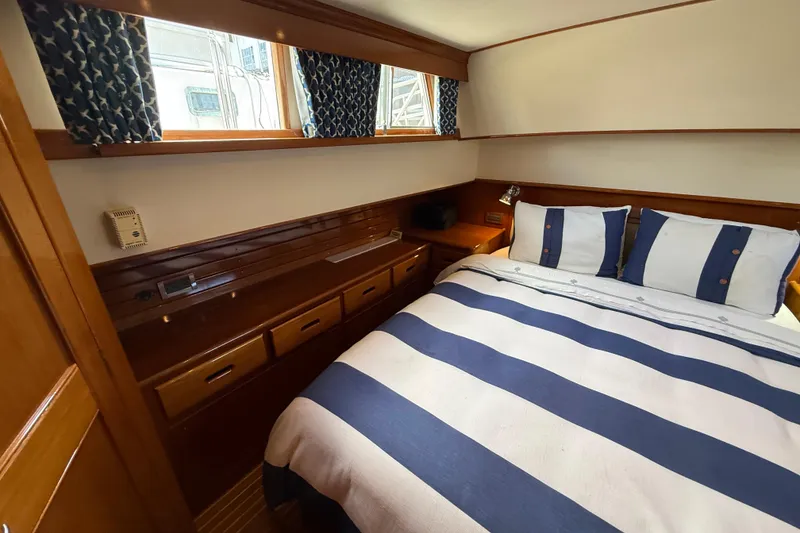 Slide: The Image of Cozy bedroom in 2002 Grand Banks 42 Classic yacht with striped bedding and wooden cabinetry. - 37