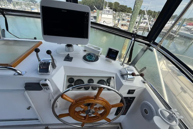 Slide: The Image of Helm of 2002 Grand Banks 42 Classic yacht with navigation equipment and wooden steering wheel. - 54