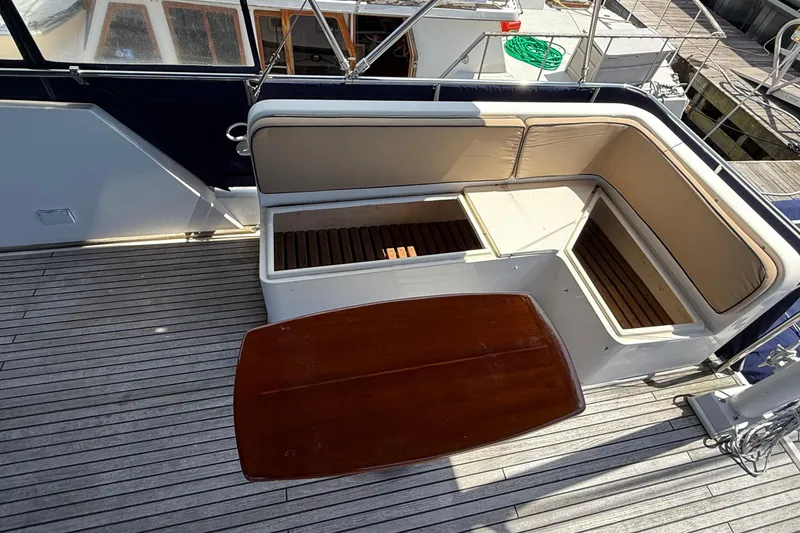 Slide: The Image of 2002 Grand Banks 42 Classic yacht deck with cushioned seating and wooden table. - 63