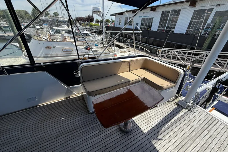 Slide: The Image of Grand Banks 42 Classic 2002 yacht deck with cushioned seating and wooden table. - 64