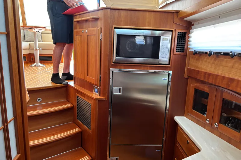 Slide: The Image of 2021 Sabre 48 Salon Express interior with wooden cabinetry, microwave, and stainless steel fridge. - 17